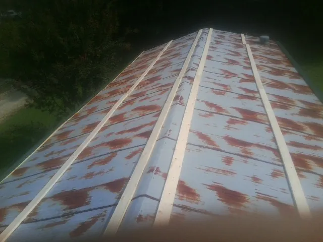 Rusted metal roof panels with new wood purlins before replacement — Storm Damage Roof Repair in Brownville by Roofing Brothers